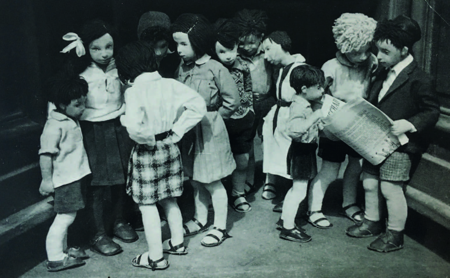 Puppengruppe mit der Künstlerin selbst mittendrin im weißen Kittel